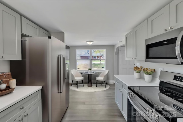 kitchen featuring light countertops, stainless steel appliances, baseboards, and light wood-style floors