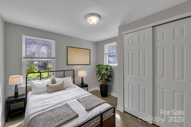 bedroom with baseboards, dark wood-type flooring, and a closet