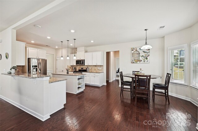 9937 Travertine Trl, Davidson, NC 28036 - kitchen with stainless steel appliances, decorative backsplash, dark wood-type flooring, a kitchen island, and light stone counters