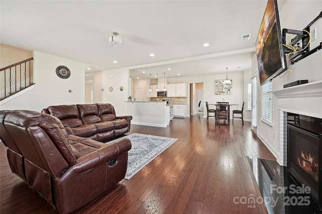 9937 Travertine Trl, Davidson, NC 28036 - living room with dark wood-style floors, a glass covered fireplace, stairs, recessed lighting, and baseboards