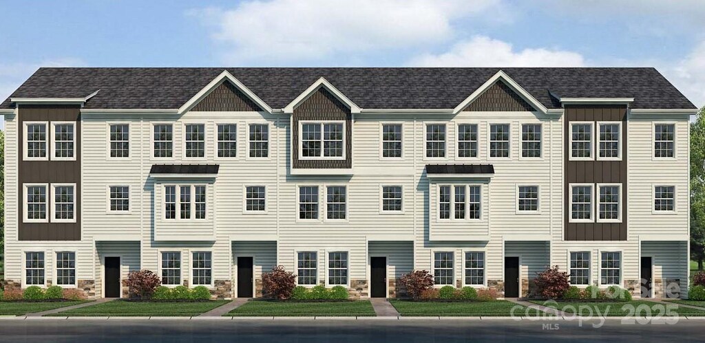 townhome / multi-family property with board and batten siding, stone siding, and a front yard
