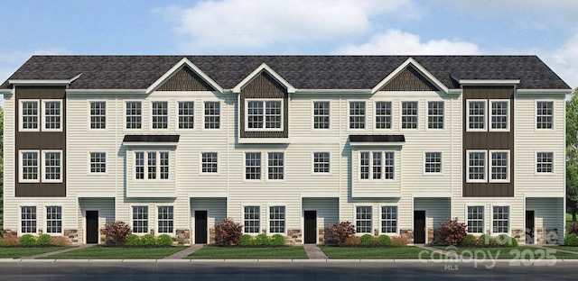 townhome / multi-family property with board and batten siding, stone siding, and a front yard