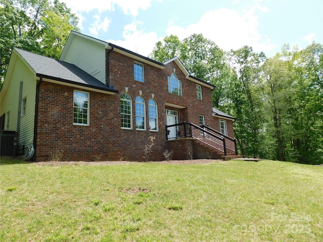 back of house featuring central air condition unit, a lawn, and brick siding
