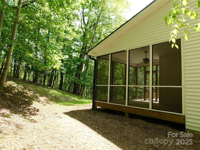 view of side of home with ceiling fan and a sunroom