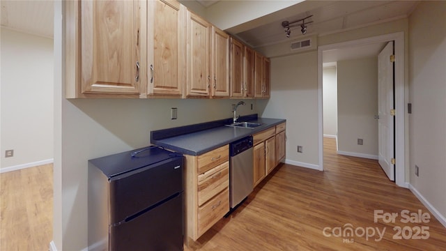 kitchen with a sink, dishwasher, wood finished floors, dark countertops, and light brown cabinets