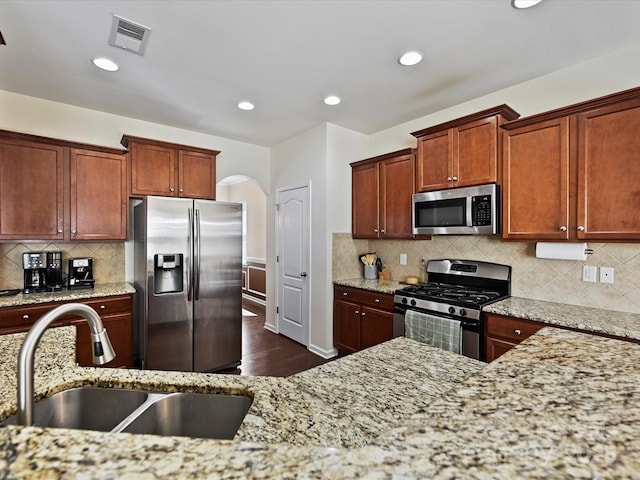11621 Red Knoll Ln, Pineville, NC 28134 - kitchen featuring stainless steel appliances, a sink, arched walkways, light stone countertops, and recessed lighting