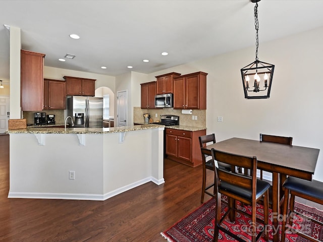 11621 Red Knoll Ln, Pineville, NC 28134 - kitchen featuring stainless steel appliances, a peninsula, dark wood-style flooring, a breakfast bar area, and recessed lighting