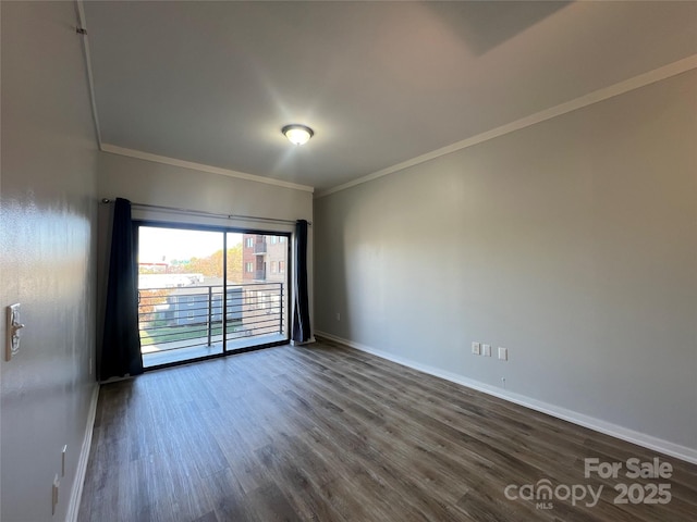 spare room featuring baseboards, dark wood-style floors, and crown molding