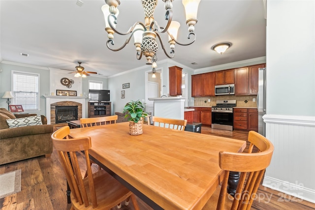 9113 Cinder Ln, Huntersville, NC 28078 - dining area with a stone fireplace, ceiling fan with notable chandelier, crown molding, and wood finished floors