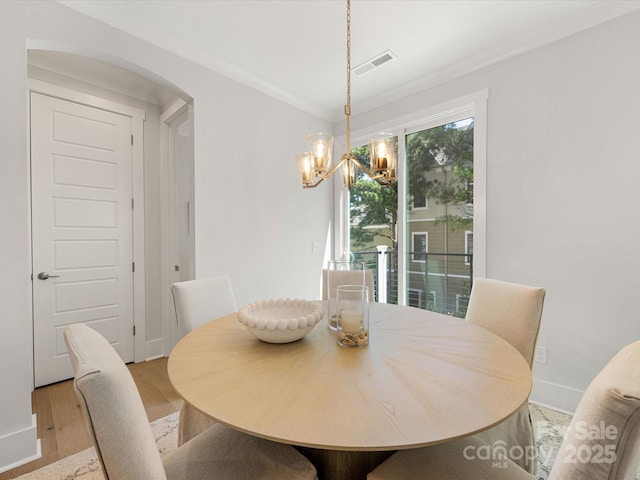1413 Kenilworth Ave, Charlotte, NC 28203 - dining area with a chandelier, wood finished floors, crown molding, and arched walkways