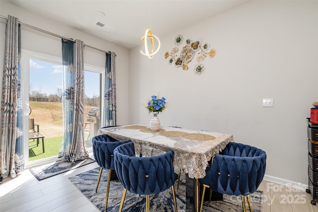dining room with baseboards, light wood-style flooring, and visible vents