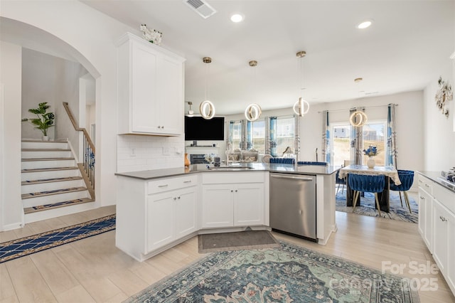 kitchen with white cabinetry, tasteful backsplash, stainless steel dishwasher, visible vents, and light wood-style flooring
