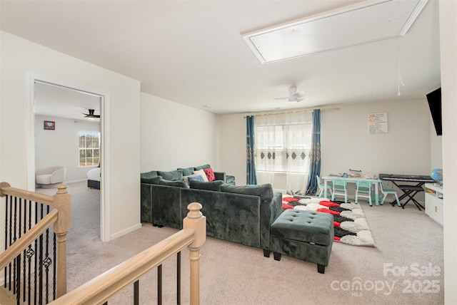 carpeted living room with baseboards and attic access