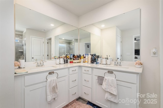 bathroom featuring double vanity, a sink, and a shower stall