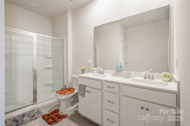 bathroom featuring a stall shower, double vanity, toilet, and a sink