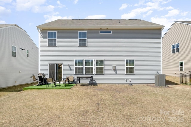 back of property with central air condition unit and a yard