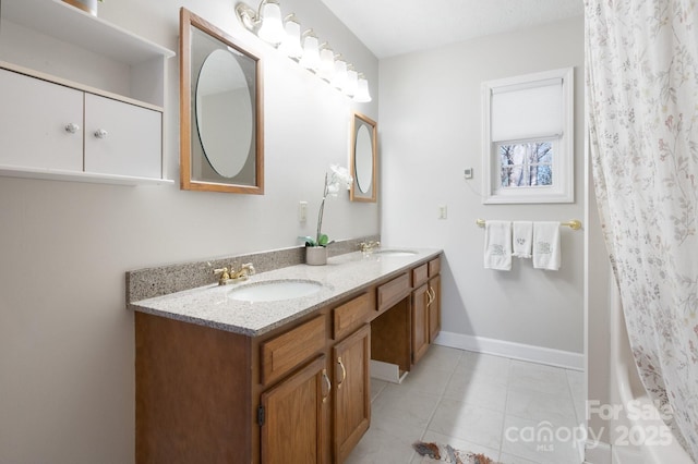full bathroom with tile patterned floors, double vanity, a sink, and baseboards