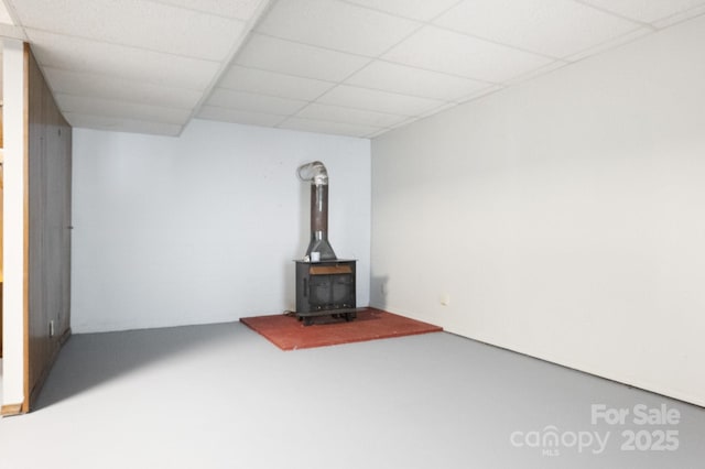 below grade area featuring a wood stove and a paneled ceiling