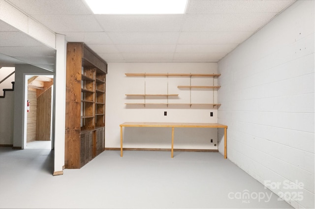 basement featuring stairs and a drop ceiling