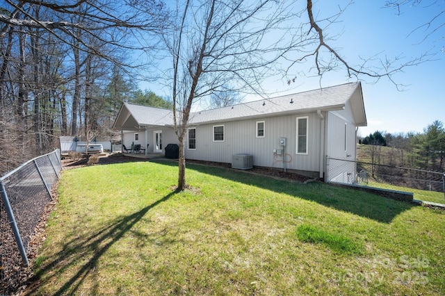 rear view of property with a fenced backyard, a lawn, and roof with shingles