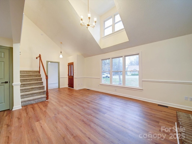 1312 Kensington Pl, Monroe, NC 28112 - unfurnished living room with stairs, visible vents, light wood-style flooring, and a notable chandelier