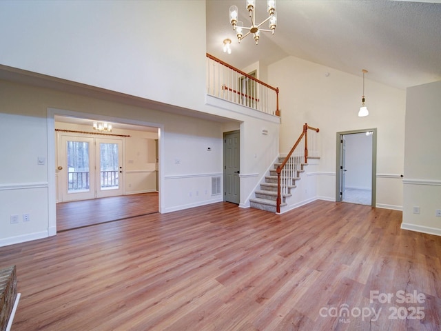 1312 Kensington Pl, Monroe, NC 28112 - unfurnished living room featuring stairs, a notable chandelier, visible vents, and wood finished floors