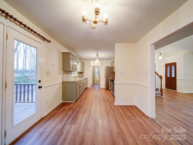 1312 Kensington Pl, Monroe, NC 28112 - kitchen featuring light countertops, an inviting chandelier, a sink, light wood finished floors, and appliances with stainless steel finishes