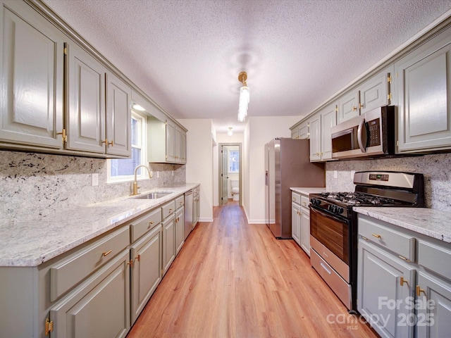 1312 Kensington Pl, Monroe, NC 28112 - kitchen with a sink, light wood finished floors, tasteful backsplash, gray cabinetry, and stainless steel appliances