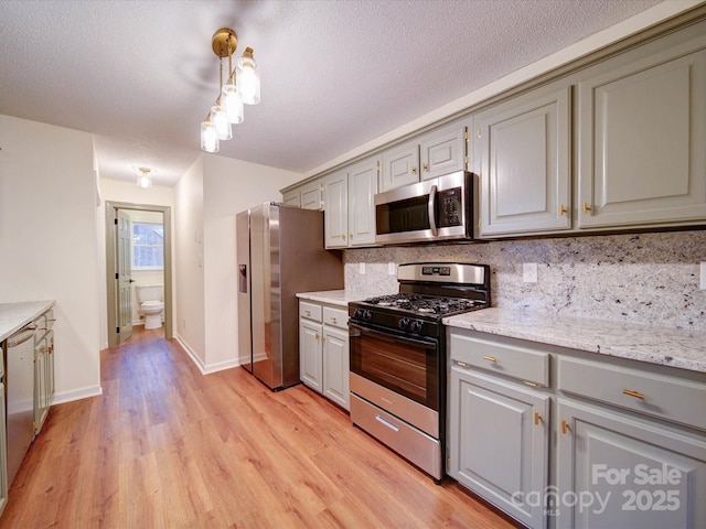 1312 Kensington Pl, Monroe, NC 28112 - kitchen with backsplash, light wood finished floors, a textured ceiling, gray cabinetry, and stainless steel appliances