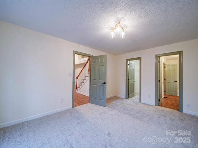 1312 Kensington Pl, Monroe, NC 28112 - unfurnished bedroom featuring baseboards, a walk in closet, carpet, and a textured ceiling