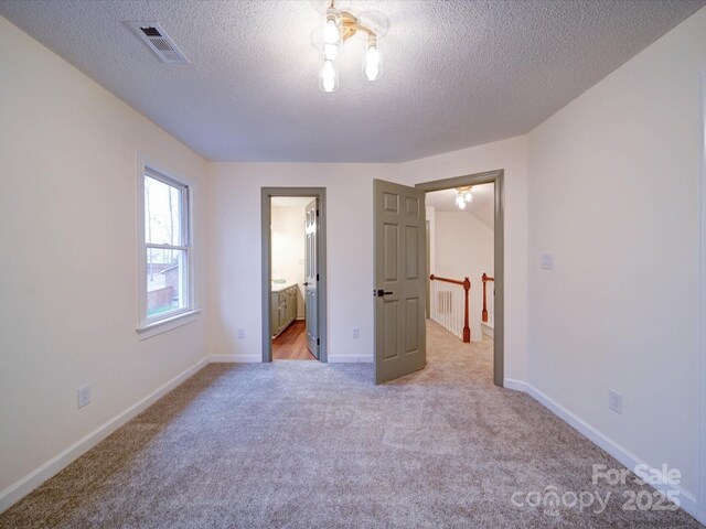1312 Kensington Pl, Monroe, NC 28112 - unfurnished bedroom with light colored carpet, baseboards, a textured ceiling, ensuite bath, and visible vents