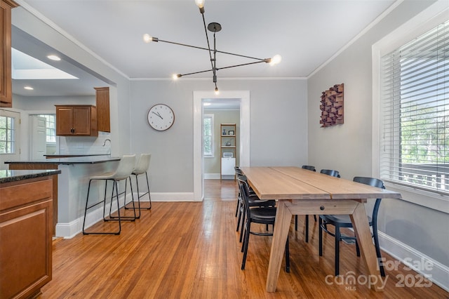 dining area featuring ornamental molding, baseboards, and light wood-type flooring