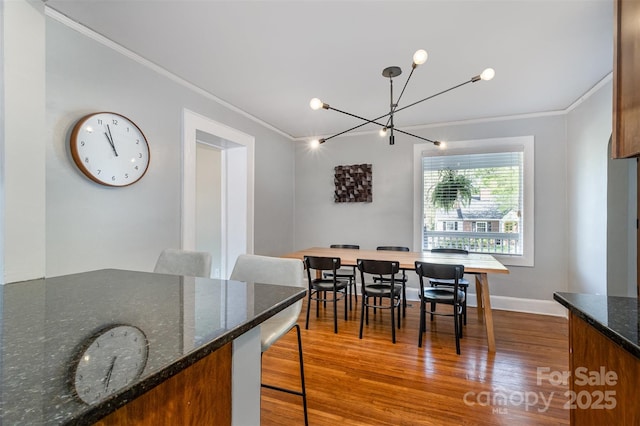 dining space featuring ornamental molding, wood finished floors, and an inviting chandelier