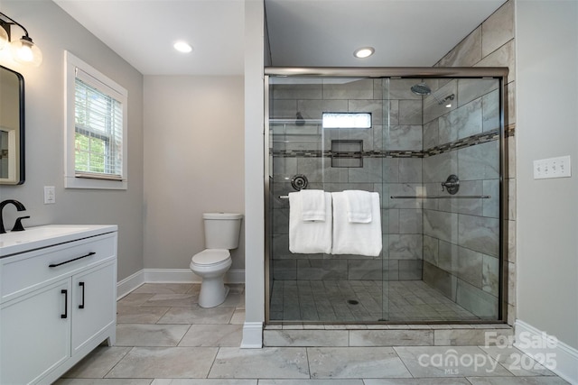 bathroom with a shower stall, baseboards, toilet, and vanity