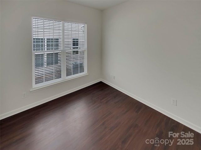 unfurnished room featuring dark wood-type flooring and baseboards