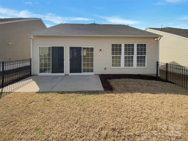 back of house with fence, a shingled roof, a patio, and a yard