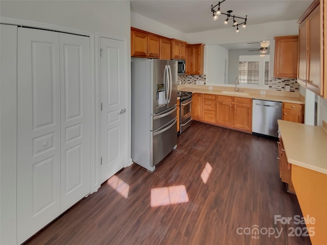 kitchen with tasteful backsplash, a sink, dark wood-style floors, a ceiling fan, and appliances with stainless steel finishes