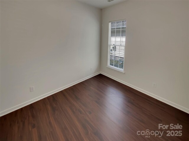 unfurnished room with dark wood-type flooring and baseboards