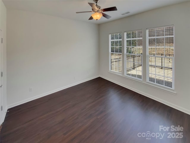 spare room with baseboards, visible vents, ceiling fan, and dark wood-style floors