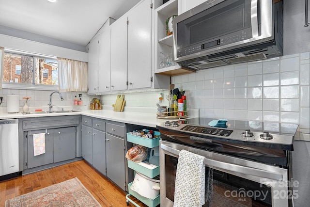 3407 14th Ave SW, Hickory, NC 28602 - kitchen with appliances with stainless steel finishes, gray cabinetry, backsplash, open shelves, and light wood-type flooring