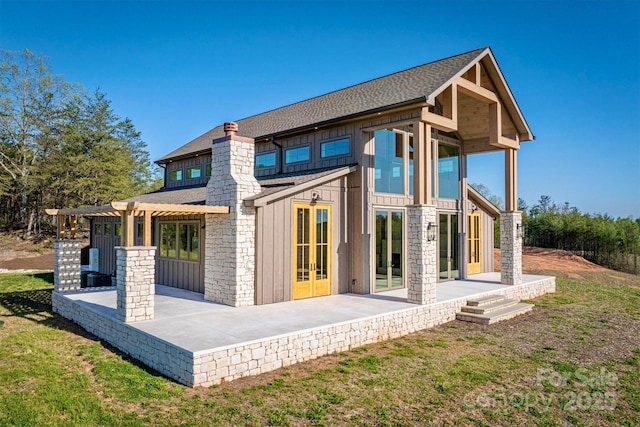 rear view of house with board and batten siding, a patio, roof with shingles, french doors, and a pergola