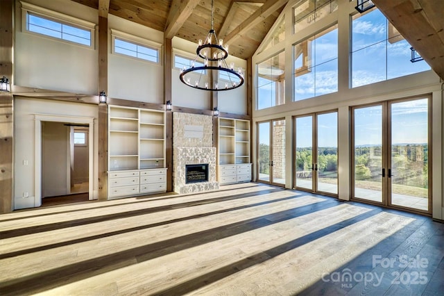 unfurnished living room featuring beamed ceiling, a fireplace, high vaulted ceiling, wood ceiling, and french doors