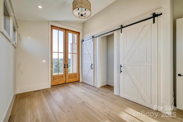 doorway featuring recessed lighting, a barn door, light wood-style floors, a notable chandelier, and baseboards