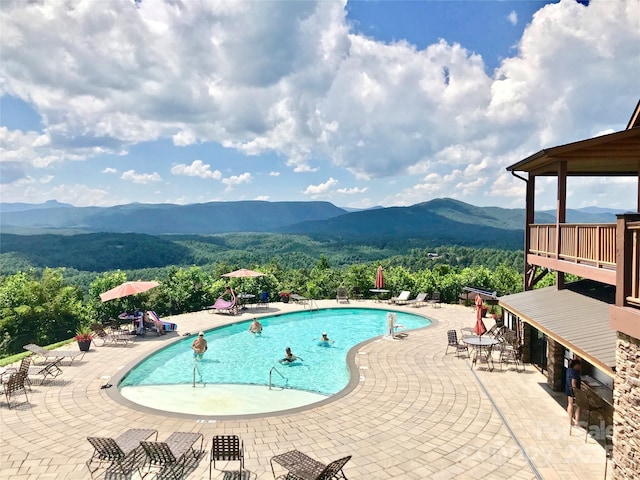 pool with a patio area and a mountain view