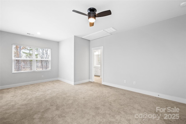 carpeted empty room with a ceiling fan, baseboards, attic access, and visible vents