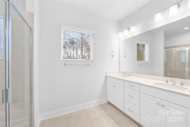 bathroom featuring baseboards, double vanity, a sink, and a stall shower