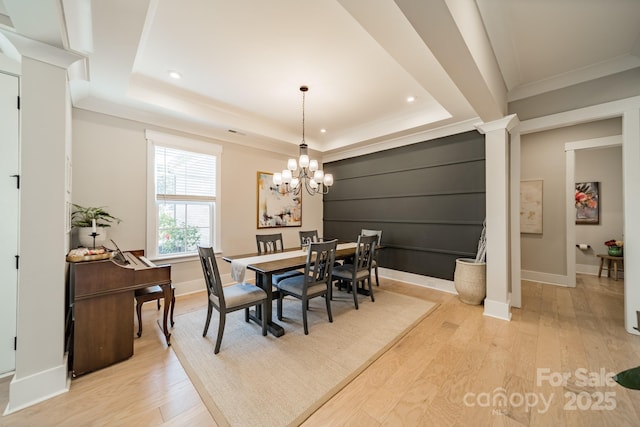 dining room with a notable chandelier, a tray ceiling, baseboards, and light wood-type flooring