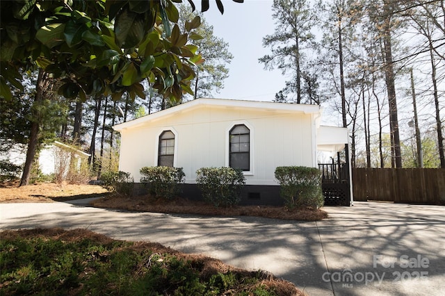 view of front facade with driveway, crawl space, and fence