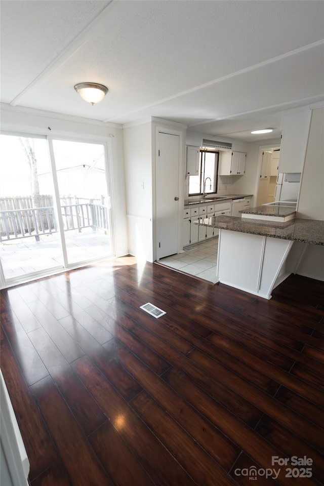 kitchen featuring a peninsula, visible vents, a sink, and light wood-type flooring