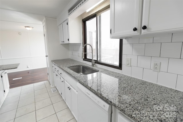 kitchen with light tile patterned flooring, dishwasher, white cabinetry, a sink, and backsplash